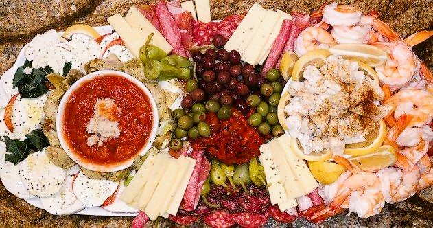 A platter of various cheeses and meats on a marble countertop.